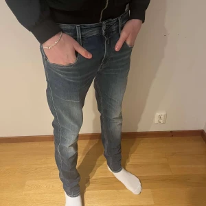 Replay Anbass jeans blå straight fit - Snygga blå Replay Anbass jeans med klassisk femficksdesign och raka ben. Jeansen har en mörk tvätt med lätt slitning framtill. Storlek W30 L32 hör av er vid funderingar