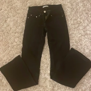 Svarta bootcut jeans från Perfect Jeans - Svarta jeans från Perfect Jeans i storlek 32 med bootcut passform. Klassisk femficksdesign med snygga silverfärgade knappar på bakfickorna och dragkedja framtill. Jeansen har normal midja och är tillverkade i ett mjukt jeansmaterial. Väldigt low waist.