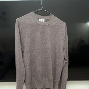 Beige stickad tröja från Sandö - En stilren beige stickad tröja från Sandö i storlek S. Tröjan har rund halsringning, ribbade muddar och lång ärm. Perfekt för lager-på-lager och enkel att matcha med jeans eller chinos.