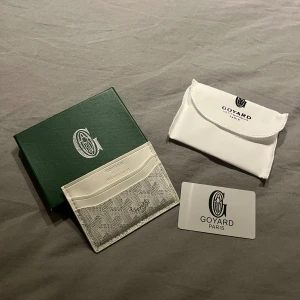 Vit plånbok från Go4ard  - Snygg och stilren vit plånbok från Go4ard med klassiskt mönster och flera fack för kort. Kommer med original ask, dustbag och autenticitetskort. Perfekt för dig som gillar exklusiva accessoarer med unik design.