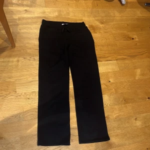 Svarta mjukisbyxor från 157, storlek M - Svarta mjukisbyxor från 157 i storlek M. Byxorna har rak passform, resår i midjan med snörning och är tillverkade i mjukt material som känns skönt mot huden. Perfekta för chill eller träning. Snyggt minimalistiskt utseende utan synliga loggor.