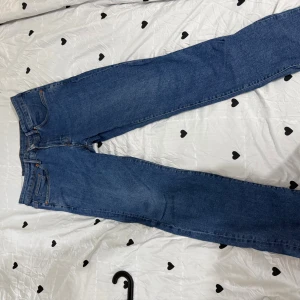 Blå raka jeans från Levi's - Säljer ett par klassiska blå jeans från Levi's med rak passform och fem fickor. Jeansen har en tidlös look med normal midja och är tillverkade i slitstarkt denim. Perfekta för dig som gillar enkel och clean stil.