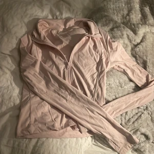 Zipup tränings tröja från Gina tricot  - Säljer en ljusrosa tränings tröja från Gina Tricot i storlek 158/164. Tröjan har hel dragkedja framtill, långärmade ärmar och är gjord i mjukt syntetmaterial. Perfekt för dig som gillar sportig och clean stil.