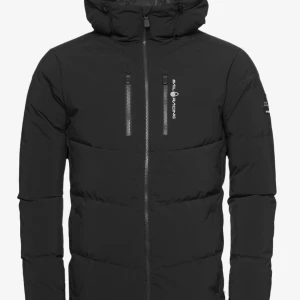 Svart pufferjacka från Sail Racing - Svart pufferjacka från Sail Racing med huva och två vertikala bröstfickor med dragkedja. Jackan har en stilren look med logotyp på bröstet och ärmarna, samt hel dragkedja framtill. Perfekt för kalla dagar och snygg till streetwear.