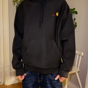 Svart hoodie från Carhartt med huva - Svart hoodie från Carhartt med gul logga och röd text på bröstet. Använd endast 1 gång. Nypris 1200kr, mitt pris 600kr. Hör gärna av er vid intresse😁😎 