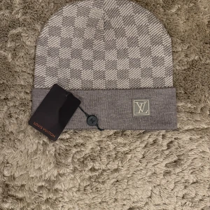 Grå Rutig mössa - Exklusiv grå rutig mössa – en stilren och tidlös accessoar som kombinerar lyx och komfort. Perfekt för både vardag och mer uppklädda tillfällen.  ♦️ One size – stretchig passform ⚜️ Helt nytt skick ♦️ Premiumkvalitet med elegant rutmönster