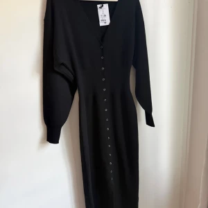 Svart långärmad klänning med knappar - Populär Svart långklänning från Gina Tricot i storlek S. Klänningen har en djup v-ringning, långa ärmar och knappar längs hela framsidan. Materialet är mjukt och stickat, vilket ger en skön känsla och snygg passform. Prislapp kvar och endast testad