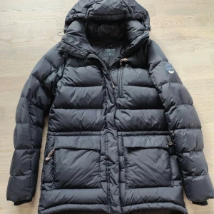 Peak Performance dunjacka  - Svart Peak Performance dunjacka med huva. Stl M. Jackan har två fickor framtill och en logotyp på vänster ärm. Perfekt för kalla dagar. I mycket fint skick! Dyr i inköp!