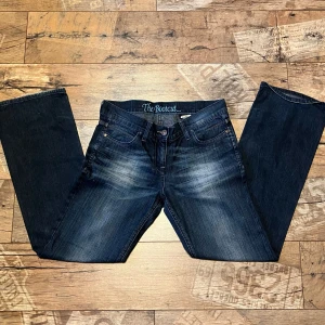 Bootcut jeans från Next, mörkblå - Mörkblå bootcut jeans från Next med snyggt slitna detaljer och klassisk femficksdesign. Jeansen har normal passform och är tillverkade i stretchig denim med bomull och elastan för extra komfort