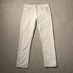 Vita jeans från Nudie Jeans 32/32 - Snygga vita jeans från Nudie Jeans i klassisk femficksmodell. Byxorna har raka ben, normal passform och är tillverkade i mjukt bomullstyg. Detaljer som Nudie-logga på bakfickan och läderpatch i midjan ger en clean och stilren look.