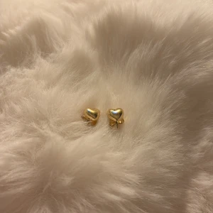 Guldiga hjärtformade örhängen - Små och söta örhängen i form av hjärtan med en blank guldig finish. 