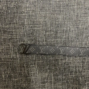 Svart Louis Vuitton bälte i skinn - Säljer ett svart bälte från Louis Vuitton med klassiskt LV-monogram och diskret mönster. Bältet är gjort i äkta skinn och har en stilren LV-spänne i svart metall. Perfekt accessoar för att lyfta din outfit med en lyxig touch.