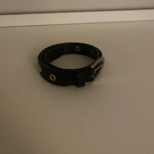 Svart bälte med silverfärgade nitar - Säljer ett svart bälte med silverfärgade metallnitar och spänne. Bältet har en klassisk, rak form och är tillverkat i skinnimitation. Perfekt för att ge jeansen en cool touch med detaljerna i metall.
