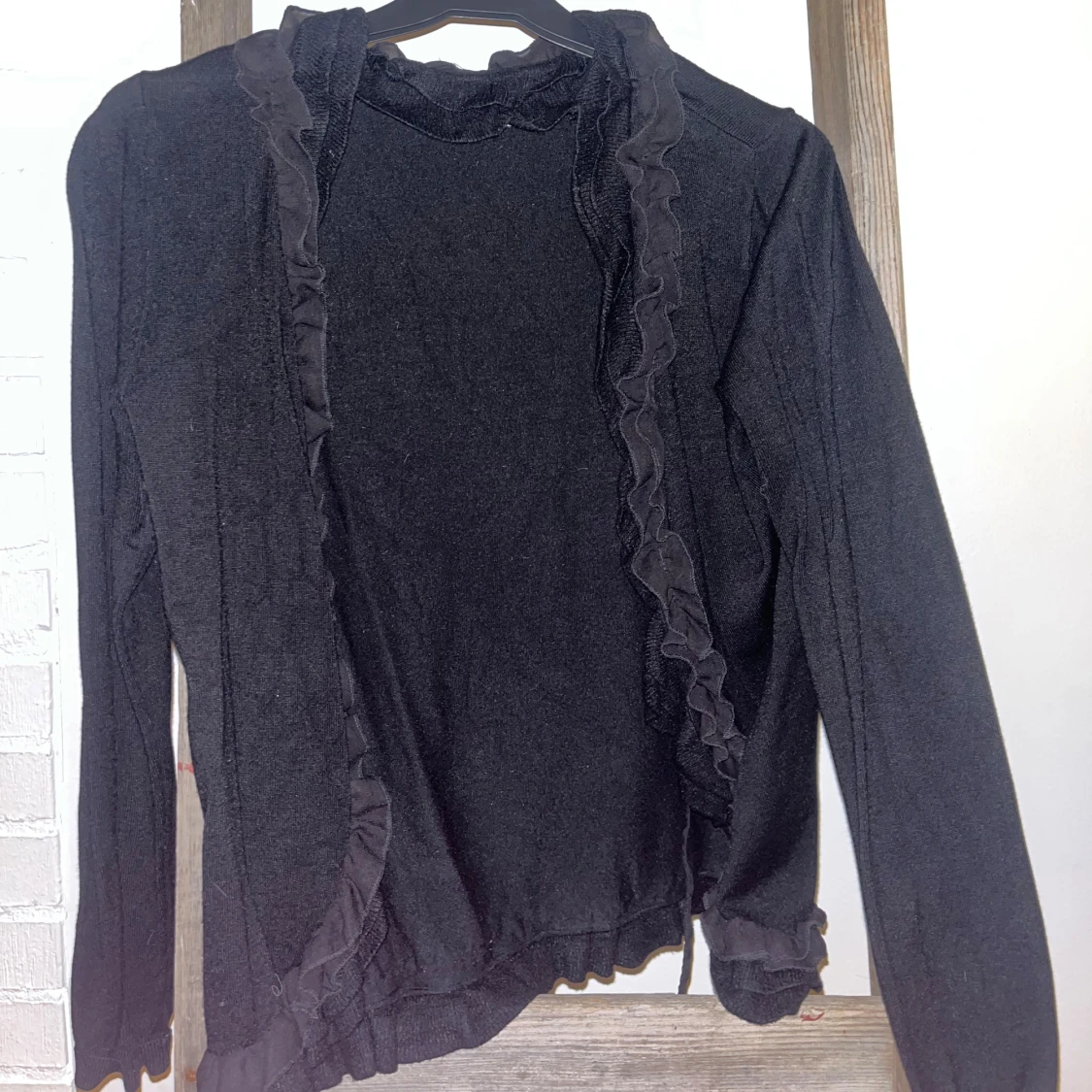 Svart kofta med volangdetaljer