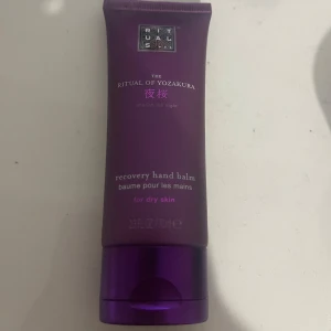 Rituals The Ritual of Yozakura hand balm - En lila tub med recovery hand balm från Rituals, The Ritual of Yozakura. Handkrämen är speciellt framtagen för torr hud och kommer i en smidig förpackning på 70 ml. Perfekt att ha i väskan för återfuktade händer.