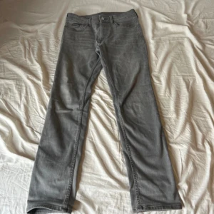 Grå jeans från Calvin Klein - Säljer ett par snygga grå jeans från Calvin Klein med klassisk femficksdesign och logga på bakfickan. Jeansen har raka ben och normal passform, tillverkade i mjukt bomullsmaterial med lite stretch för extra komfort.