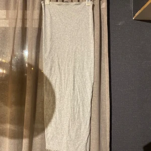 Ljusgrå långkjol från FB Sister - En stilren ljusgrå långkjol från FB Sister i ribbad bomullsmix. Kjolen har en rak passform och är superenkel att matcha med olika toppar. Perfekt för dig som gillar en clean och avslappnad look.