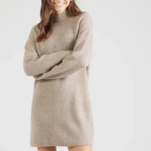 Beige stickad poloklänning - Mysig beige stickad klänning med polokrage och lång ärm. Den har en rak, loose passform och är perfekt för kyligare dagar. Enkel och stilren design som är lätt att matcha med olika accessoarer.