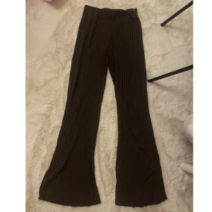 Bruna ribbade byxor med utsvängda ben - Mörkbruna ribbade bootcut byxor med skön stretch. Byxorna har en hög midja och är tillverkade i ett mjukt bekvämt material. - Bra skick Strl Xs och passar även som S   Kontakta för mer info/ fler bilder