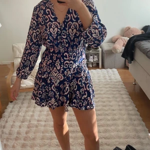 Blå mönstrad kortklänning med knappar Zara - Skön bekväm snygg kort sommarklänning från Zara köpt för 2 år sedan använd 1 gång inga defekter! Finns en dragkedja på sidan av klänningen.