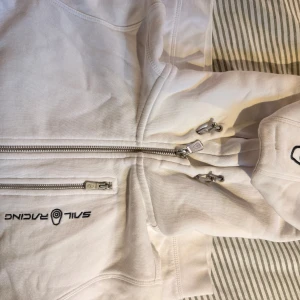 hoodie Sail Racing  - Vit hoodie från Sail Racing med hel dragkedja framtill! 