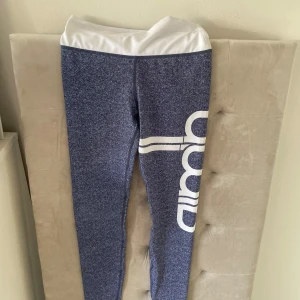 Blåmelerade leggings med vit midja - Snygga blåmelerade leggings med bred vit midja och stort vitt tryck längs ena benet. Perfekta för träning eller chill, med tight passform och stretchigt material som sitter skönt hela dagen. Tror det är storlek S🩷