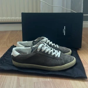 Saint Laurent grå mocka sneakers - Säljer dessa saint Laurent skor storlek 43. Dustbag, skobox och nya sko snören ingår. Hör av dig vid eventuella frågor, priset är ej hugget i sten