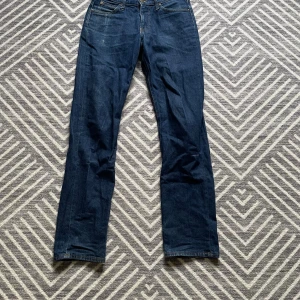 Mörkblå jeans från Lee straight fit - Snygga mörkblå jeans från Lee med klassisk femficksdesign och raka ben. Jeansen har kontrastsömmar och Lee-logga på bakfickan. Tillverkade i slitstarkt denimtyg som ger en tidlös look. Perfekta för dig som gillar enkel och stilren stil. Skulle säga att längden passar allt från 32-34