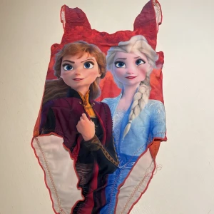 Frozen baddräkt stl 128 Ronald A/S - Superfin baddräkt med motiv från Frozen, Anna och Elsa på framsidan. Färgerna går i rött, blått och vitt med coola detaljer och tryck. Baksidan har en mix av röd, orange och lila. Perfekt för dig som älskar Disney och vill sticka ut på stranden eller i poolen.