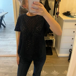 Svart spetsblus med kort ärm - Säljer en svart blus i spets med korta ärmar och rund halsringning. Blusen har ett snyggt genombrutet mönster och är lätt och luftig, perfekt för att ge outfiten en extra touch. Passar till både jeans och kjol. Storlek M men passar mig som är storlek Xs 