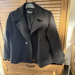 Kappa från Design by Si - Svart snygg kappa från design by si i storlek XS/S. Inne i kappan har tyget gått sönder (se sista bild) men är igen sydd. Perfekt till hösten.