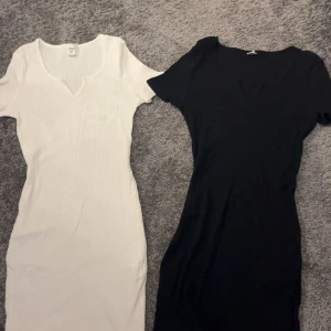 Två ribbade klänningar från SHEIN - Säljer två ribbade kortklänningar från SHEIN i storlek 14Y. En är vit och en är svart, båda med kort ärm och v-ringad hals. Klänningarna har en slim passform och är perfekta för dig som gillar enkel och stilren look.