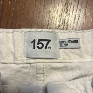 Vita raka jeans från 157 Boulevard Star - Snygga vita jeans från 157 Boulevard Star i rak modell. Byxorna har klassisk femficksdesign, bälteshällor och stängs med knapp och dragkedja. Perfekta för dig som gillar en clean och stilren look. Materialet är mjukt och bekvämt.