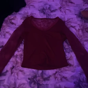 Vinröd långärmad spetsblus - Säljer en vinröd långärmad blus med transparenta spetsärmar och spetsdetaljer vid halsringningen. Toppen har v-ringad urringning och är figurnära i modellen. Perfekt för dig som vill ha något snyggt och lite extra till outfiten!!🩷 den är i storlek Xs och har används 1 gång