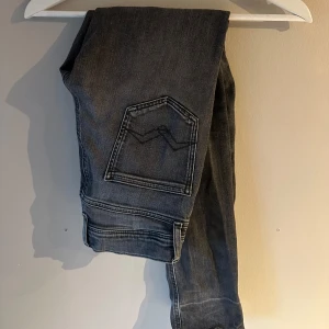 Grå jeans från Replay  - Snygga grå jeans från Replay med klassisk femficksdesign och coola kontrastsömmar. Jeansen har raka ben och en stilren bakficka med broderad detalj. Perfekta för dig som gillar en avslappnad men ändå trendig look.