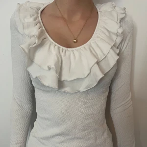 Vit volangtröja från Cider! - Supersöt vit långärmad tröja från Cider med stora volanger runt den runda urringningen. Tröjan har en lätt ribbad struktur och är figurnära. 💕 Köparen står för frakten!