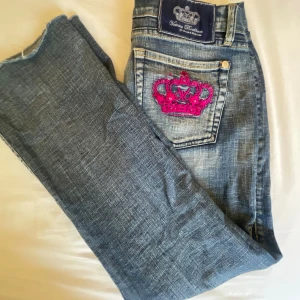 Victoria Beckham jeans rock and republic  med krona  - OBS KAN TÄNKA MIG LÄGRE PRIS!! Skicka förslag  Mått: midja 42 (sitter långt ner på höfterna) innerben 72. Snygga blå jeans från Victoria Beckham for Rock & Republic med en cool rosa broderad krona på bakfickan. Klassisk femficksmodell med flare ben och låg midja. Jeansen har slitna detaljer och kontrastsömmar för en trendig look. 