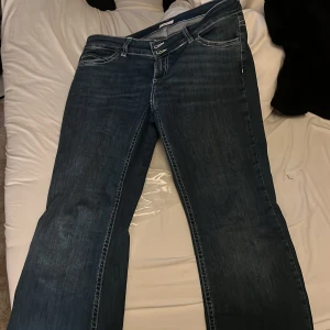 Blå bootcut jeans med broderade fickor - Snygga mörkblå jeans med bootcut passform och låg midja. Jeansen har coola broderade detaljer på bakfickorna och kontrastsömmar. Klassisk femficksmodell med dragkedja och dubbla knappar framtill. Säljer dem för att jag inte gillar hur de sitter på mig! Har tagit av lapparna men byxorna är använda 2 gånger !