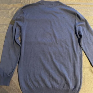 Pologarage blå tröja (Xl, mer som ett M/L) - Blå tröja från Pologarage. Storlek XL står i plagget, men den sitter mer som en M/L eftersom den är köpt utomlands (ärmarna lite kortare än normalt). Endast använd 2 gånger och i mycket bra skick. Passar både vardag och lite mer uppklätt.