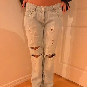 Ljusblå slitna jeans med pärldetaljer - Säljer ett par skitsnygga ljusblå jeans med slitningar. Jeansen har pärldetaljer vid fickorna och broderade bakfickor. lite oklar storlek, jag skulle säga att dem är XS /34.🌸  Jag är 165 och dem går hela vägen ner till hälarna på mig.  OBS dem är egensydda i skrevet, så sömmarna kanske inte är helt perfekta.