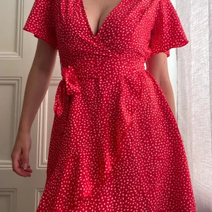 Röd omlottklänning från SHEIN S - Superfin röd omlottklänning från SHEIN i storlek S. Klänningen har korta ärmar, v-ringning och knyt i midjan. Köpt secondhand och använts någon enstaka gång av mig.