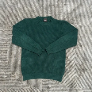 stickad tröja Oscar Jacobson grön - Säljer en mörkgrön stickad tröja från Oscar Jacobson i storlek M. Tröjan har rund halsringning, grovstickad struktur och ribbade muddar vid ärmslut och nederkant. Perfekt för kyliga dagar och enkel att matcha med jeans eller chinos.
