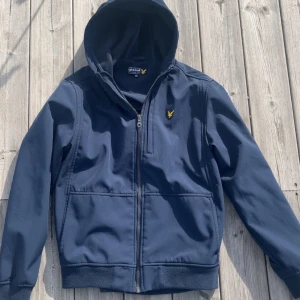 vindjacka  - Säljer en marinblå vindjacka från Lyle & Scott. Perfekt för höstiga dagar, Jackan är i nyskick utan några skador. Nypris - 950 kr.