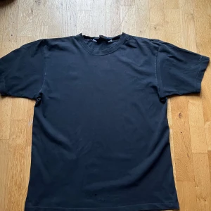 Svart t-shirt Marwin & Friends L/XL - Enkel svart t-shirt från Marwin & Friends i storlek L/XL. Klassisk rund halsringning och rak passform. Tillverkad i mjuk bomull, perfekt för en clean och avslappnad stil.