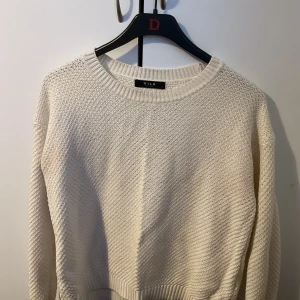 Vit stickad tröja från VILA - Säljer en vit stickad tröja från VILA med rund halsringning och lång ärm. Tröjan har ett snyggt strukturerat mönster och ribbade muddar vid ärmslut och nederkant. Perfekt för lager-på-lager under kyliga dagar.