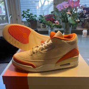 Nike Air Jordan 3 starfish TEX - Nike Air Jordan 3 sneakers i en clean beige canvas med orange detaljer på häl, sula och foder. Snygg retro-vibe med klassisk siluett, snörning och synlig Air-enhet i sulan. Perfekta för dig som vill sticka ut med stilrena och unika färgval.