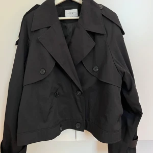 Svart trenchcoat  - Kort svart trenchcoat från Josefin HJ x NA-KD. Oversized i modellen, slutsåld på hemsidan!