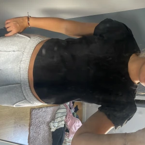 Svart croppad t-shirt - En enkel svart croppad t-shirt med korta ärmar. T-shirten har en klassisk rund halsringning och är perfekt för en avslappnad stil. Passformen är normal och materialet känns mjukt mot huden.