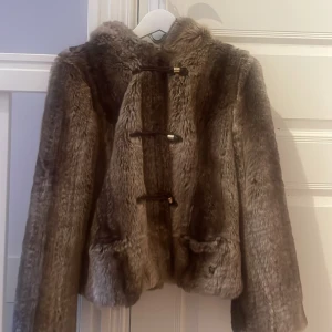 Brun pälsjacka med huva - Säljer en fluffig brun pälsjacka med huva och snygga spännen framtill. Jackan är från Juicy Couture, köpte den i USA men den har aldrig kommit till användning då det inte min stil. Storleken är en liten L, så typ M. 