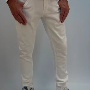 Dondup Vita slim jeansbyxor i bomull - Snygga vita jeansbyxor med slim passform och klassisk femficksdesign. Byxorna är tillverkade i mjuk bomull och har en smal siluett som sitter tajt längs benen. Perfekta för dig som gillar en stilren och fräsch look.